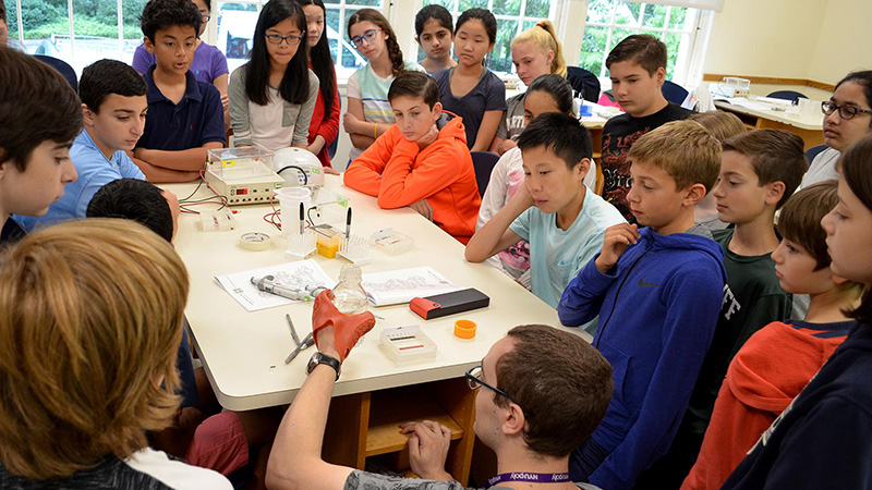 A group of students around a table observe an experiment