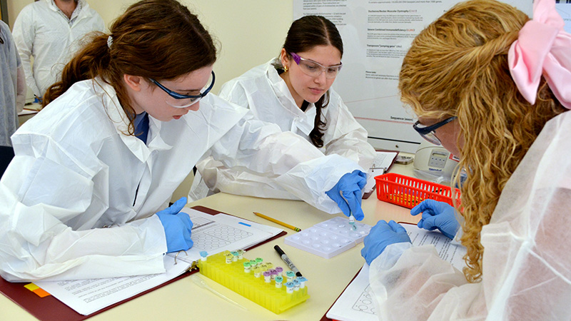 A group of students in lab coats workng on an experiemnt