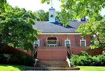 The Dolan DNA Learning Center building in Cold Spring Harbo; red brick structure surrounded by bright green trees